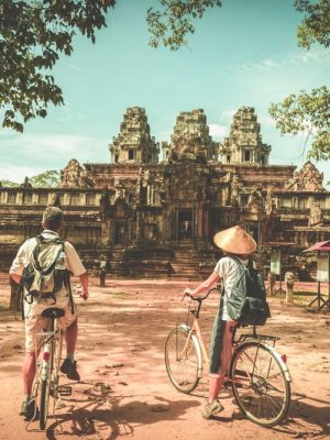 Tourist couple cycling Angkor temple Cambodia Ta Keo Eco friendly tourism traveling