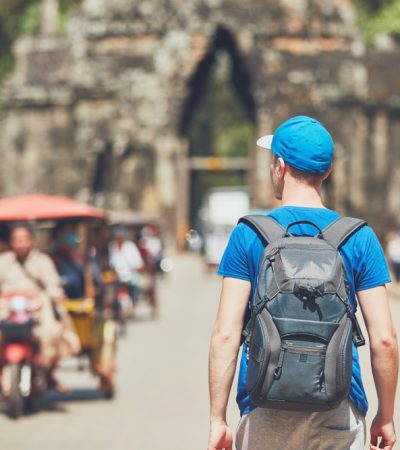 Tourist in the ancient city. Young man with backpack coming to ancient monuments Siem Reap Cambodia